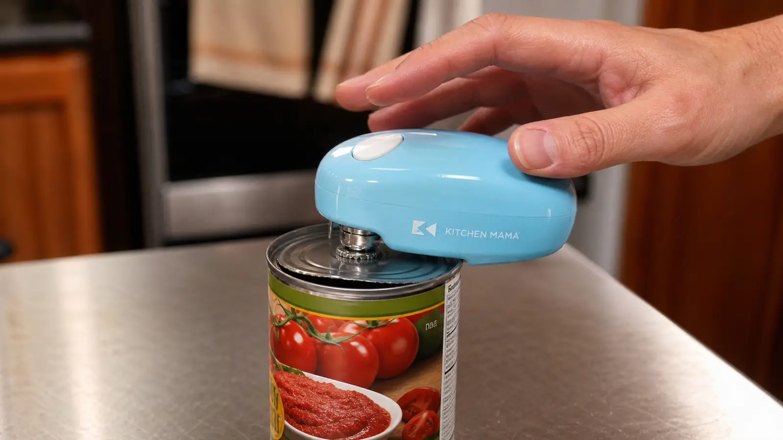 A hand clamping the electric can opener onto the rim of a can, opener beginning to rotate around the lid hands-free