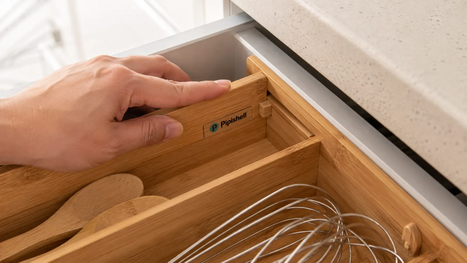 Hand testing the locking peg of the bamboo organizer against the side wall of a narrow drawer to check clearance