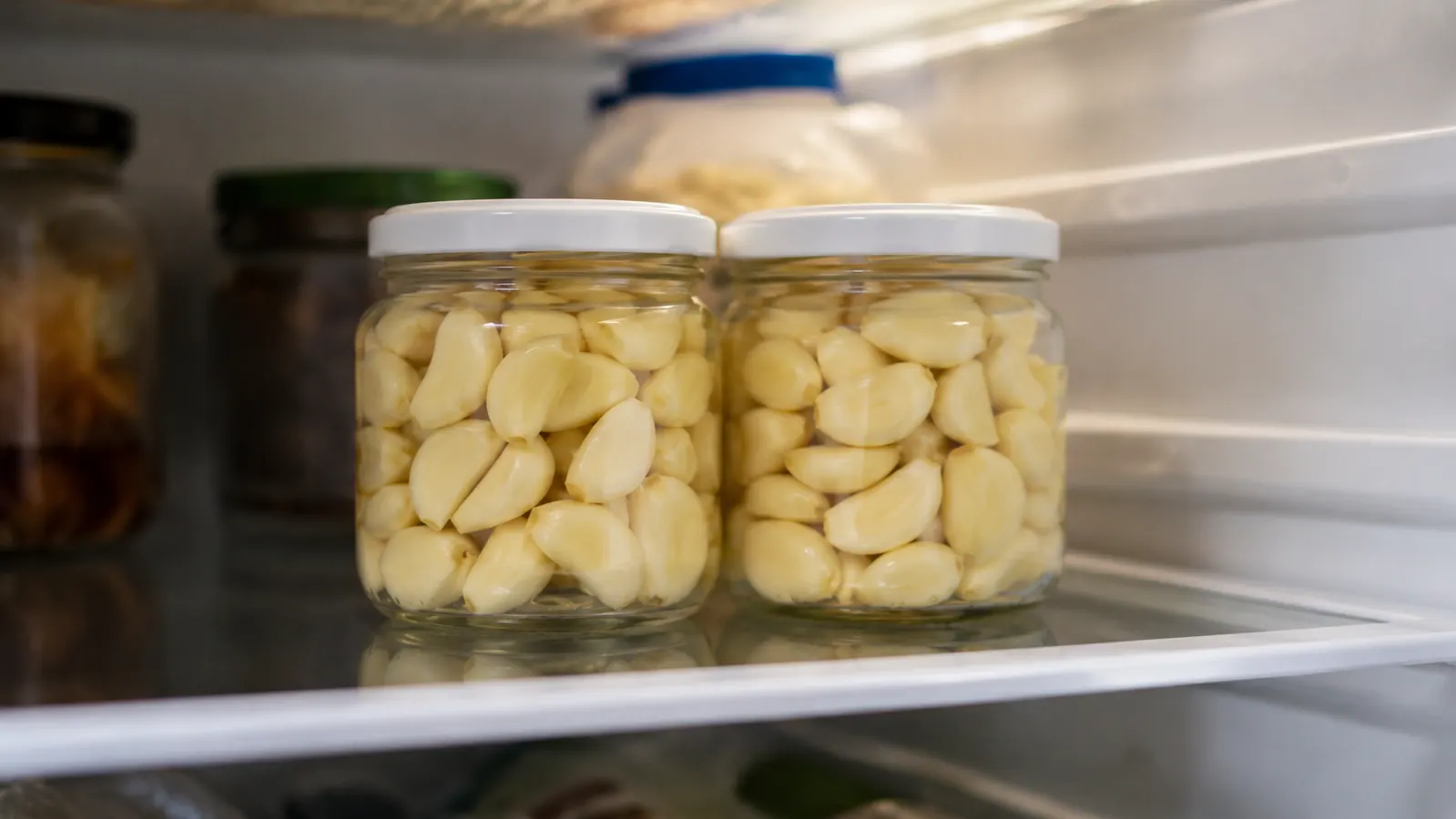 Small glass jars of pre-peeled garlic cloves stored in the refrigerator door